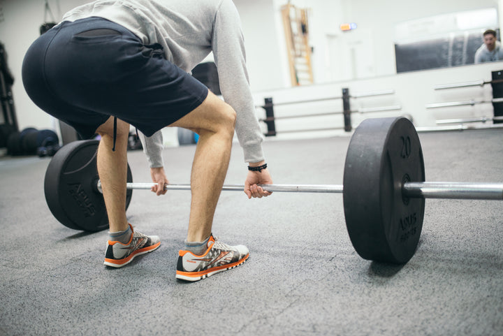 Persona realizando entrenamiento de fuerza con peso libre en gimnasio para preservar masa muscular