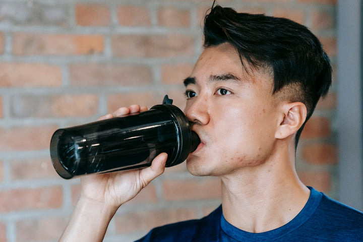 Atleta hidratándose con shaker durante entrenamiento, ilustrando el rol de la betaína anhidra en la hidratación celular
